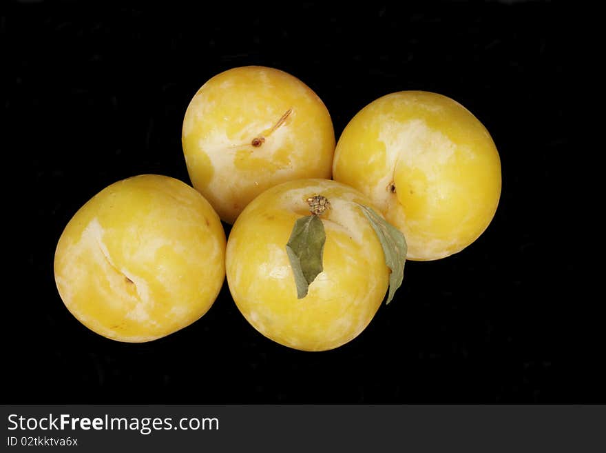 Ripe yellow plums in isolated over black