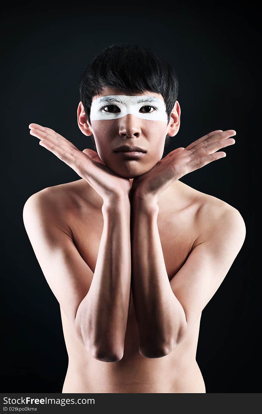 Shot of a stylish young man with painted eyes posing  over black background. Shot of a stylish young man with painted eyes posing  over black background.