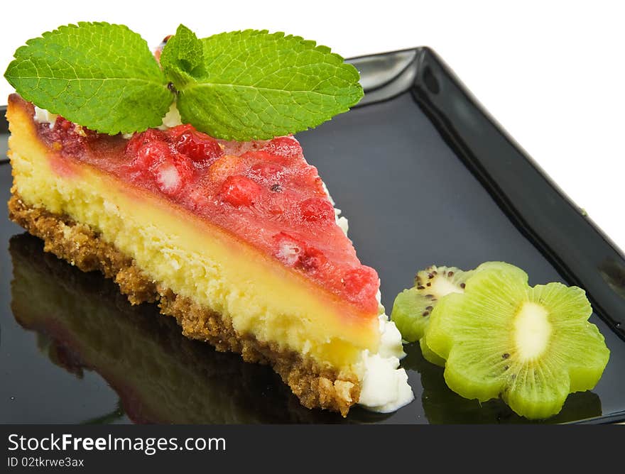 Cheesecake with strawberries on black plate isolated. Cheesecake with strawberries on black plate isolated