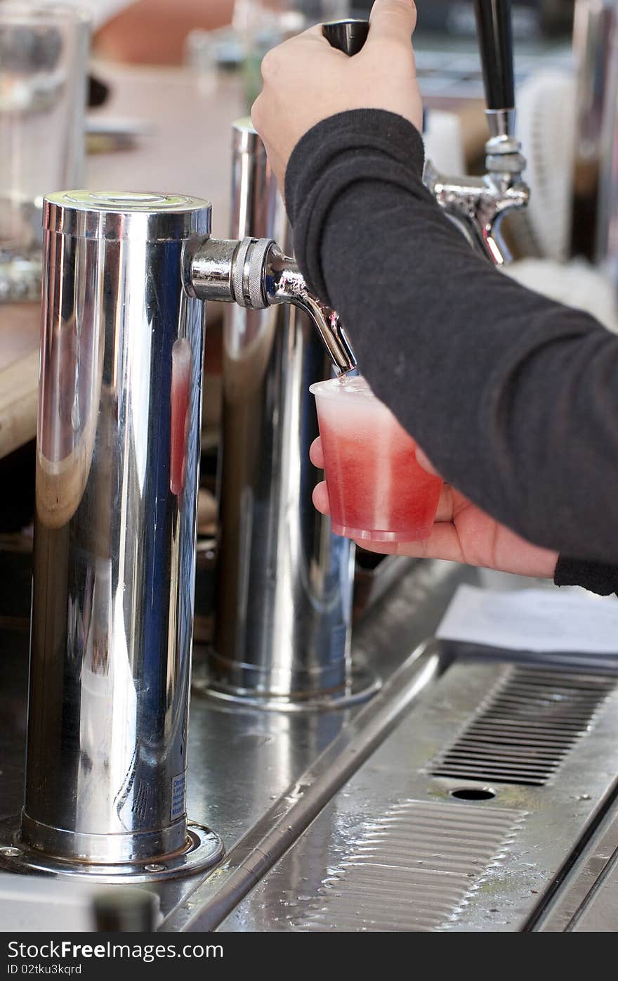 Woman serving a strawberry beer directly from the pump. Woman serving a strawberry beer directly from the pump