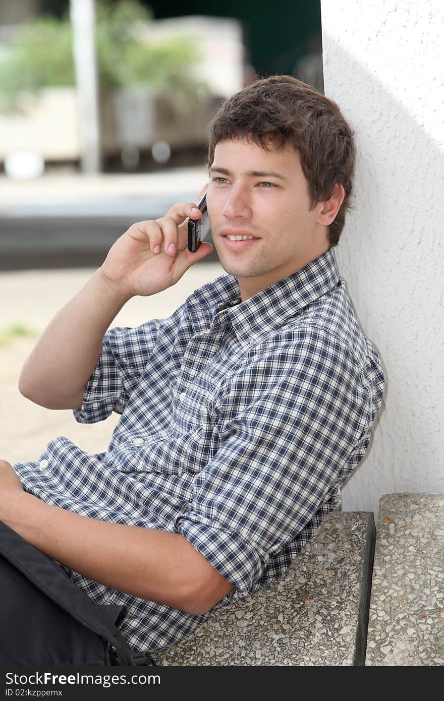 Young man sitting on the ground with mobile phone. Young man sitting on the ground with mobile phone