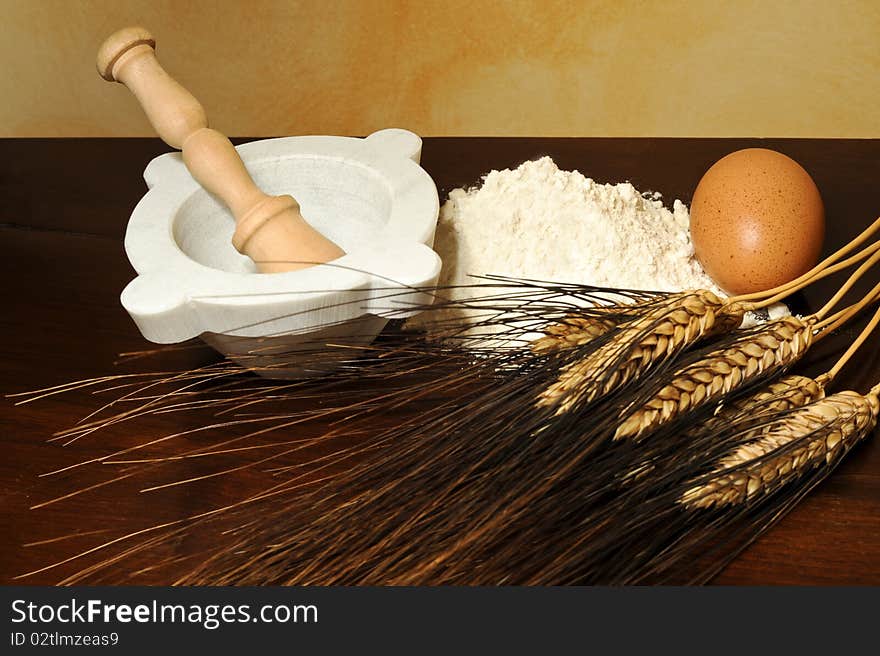 Eggs, flour, wheat ears and mortar on wood table. Eggs, flour, wheat ears and mortar on wood table