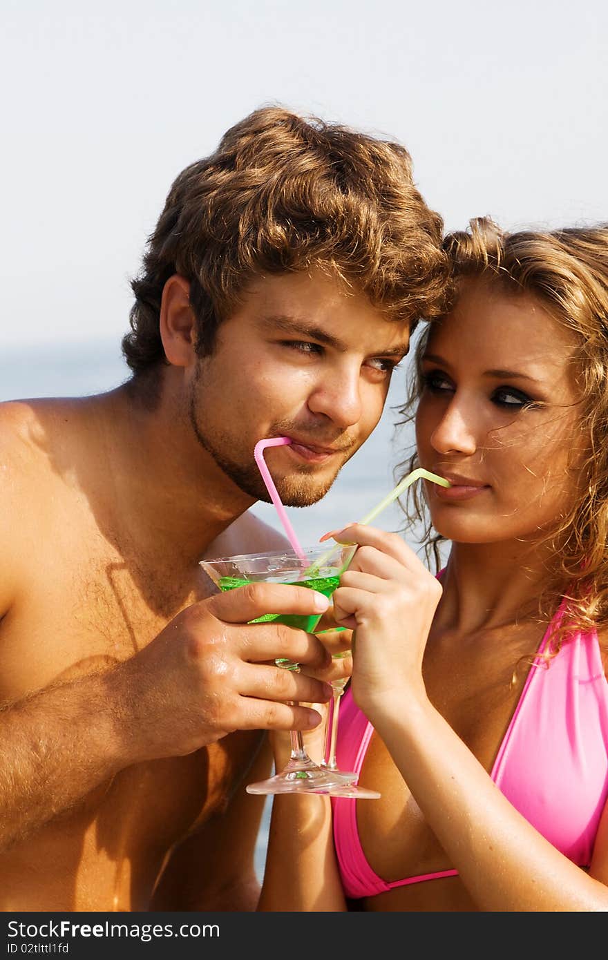 Young cheerful couple with cocktails on the seaside. Young cheerful couple with cocktails on the seaside