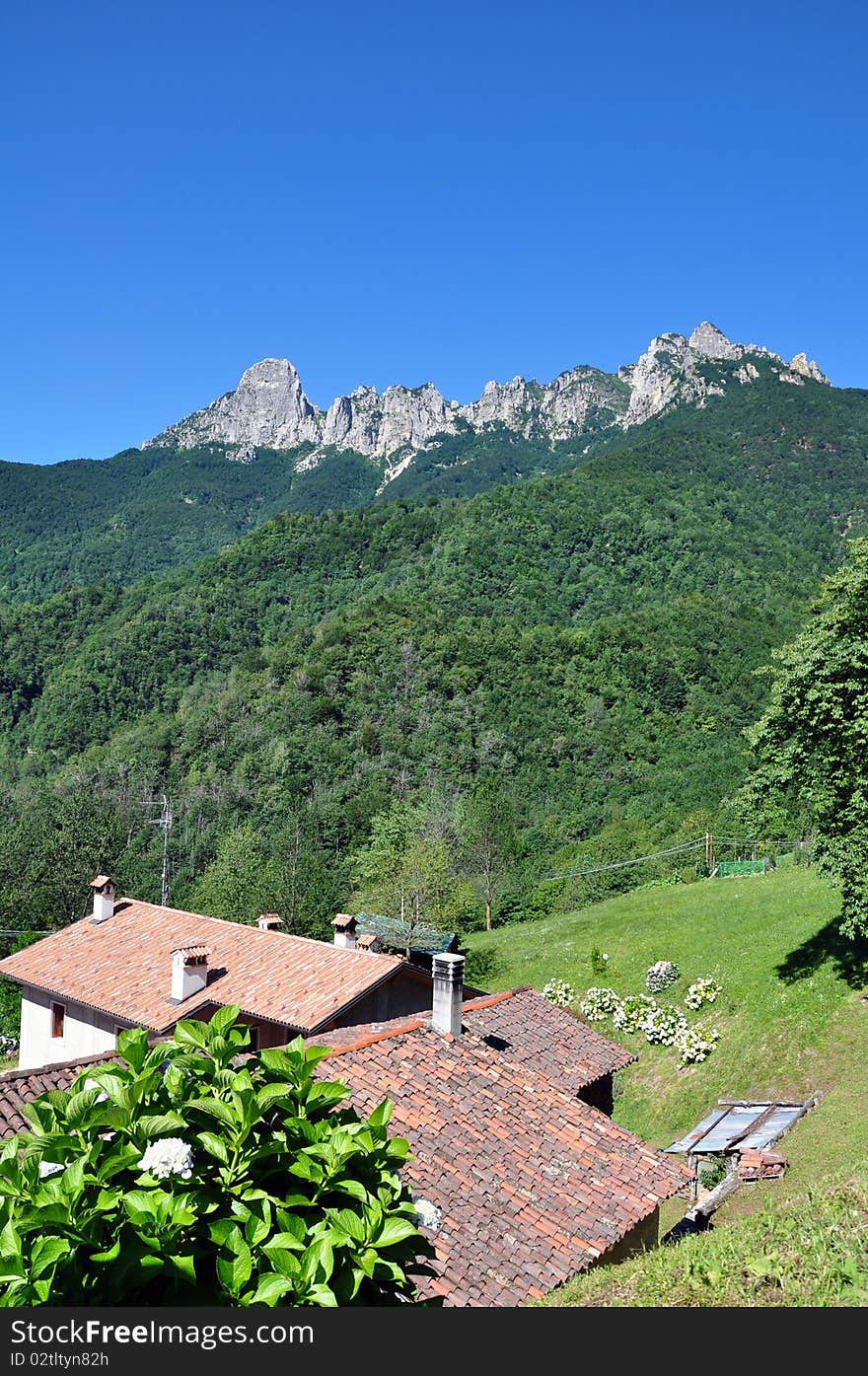 Roof of a house nestled at the foot of high mountains under a blue sky. Roof of a house nestled at the foot of high mountains under a blue sky