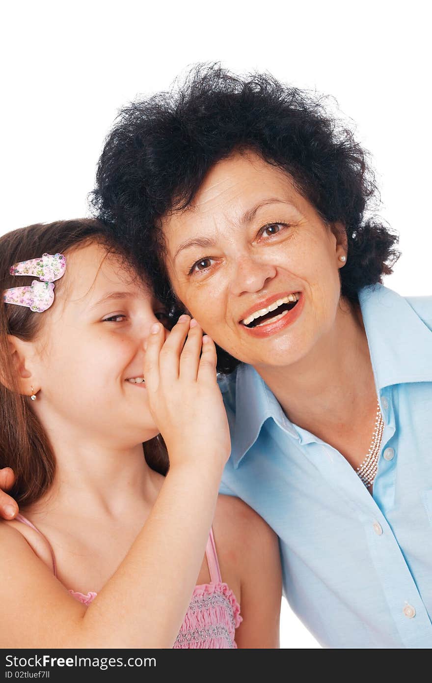 Close-up of a grandmother and her granddaughter whispering something fanny  into her ear. Close-up of a grandmother and her granddaughter whispering something fanny  into her ear.