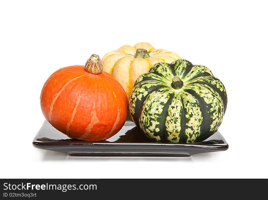 Three decorative squashes or gourds on a plate - white background.