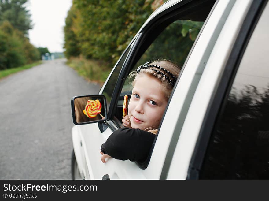 Little girl with a lollipop in his hand sitting in the car. Little girl with a lollipop in his hand sitting in the car