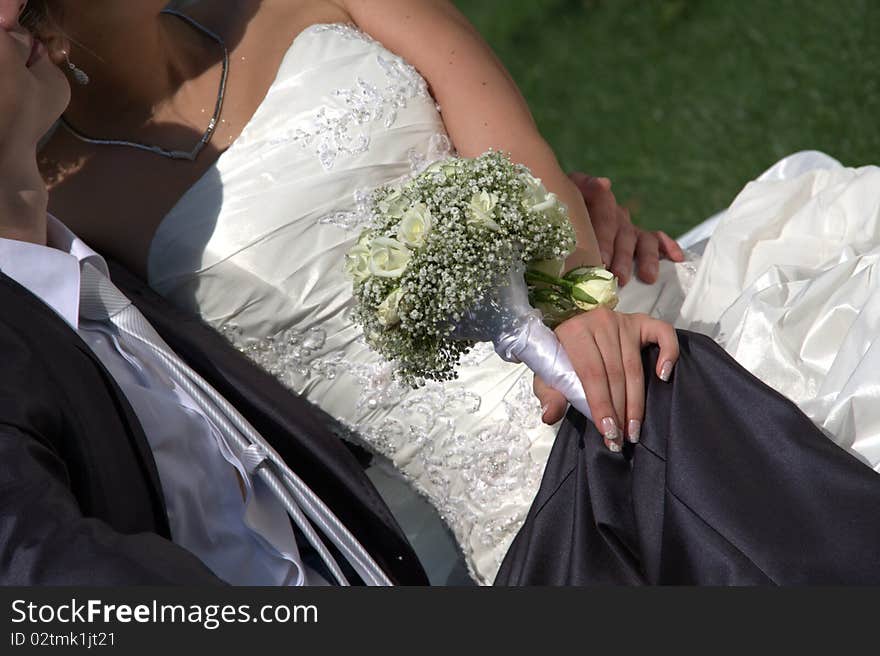 Young couple sit on a grass, fiancee of get on the hip is a wedding bouquet. Young couple sit on a grass, fiancee of get on the hip is a wedding bouquet