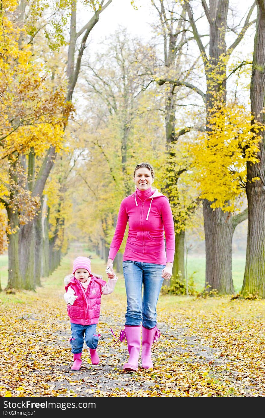 Mother with her daughter in autumnal alley