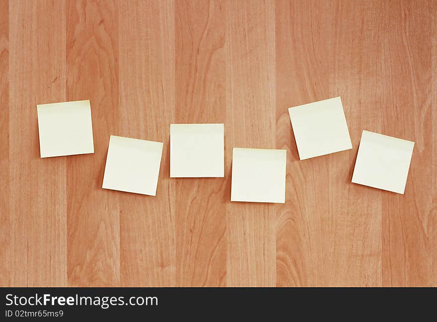 A row of sticky notes pasted on a wooden wall. A row of sticky notes pasted on a wooden wall