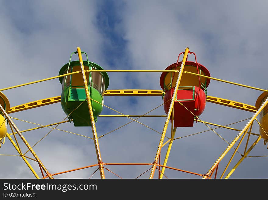 Attraction (Carousel) Ferris wheel on the background of the cloudy sky