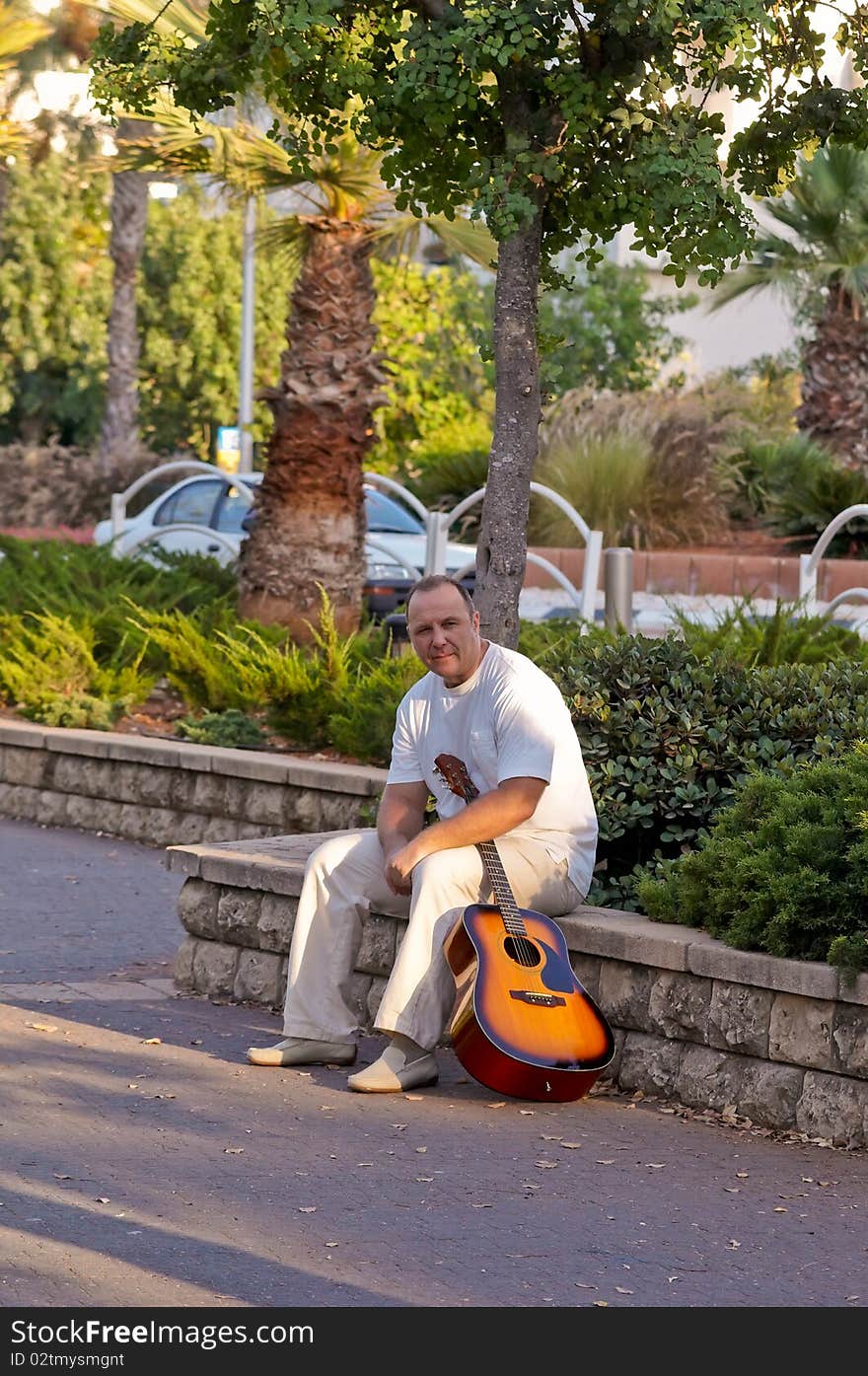 A man with a guitar in the park. A man with a guitar in the park.