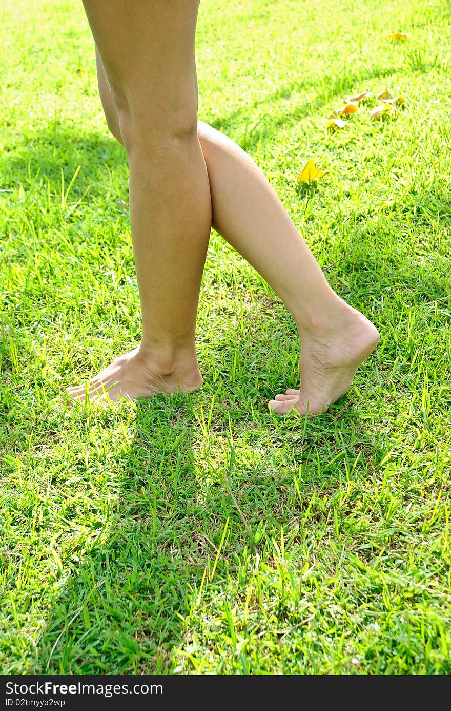 Woman leg stands on the lawn  in daytime