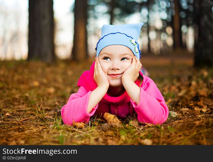 Cute happy little girl on the grass in the autumn park. Cute happy little girl on the grass in the autumn park