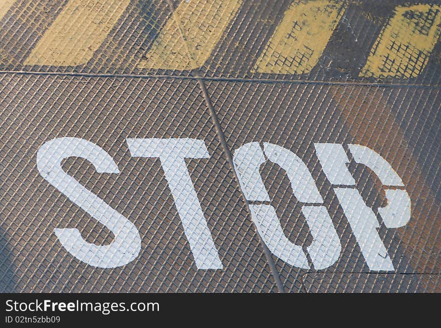 Stop and danger signs painted on rusty metal floor.