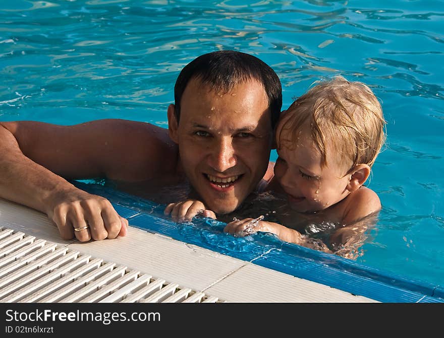 A father and his son have fun in the pool. A father and his son have fun in the pool