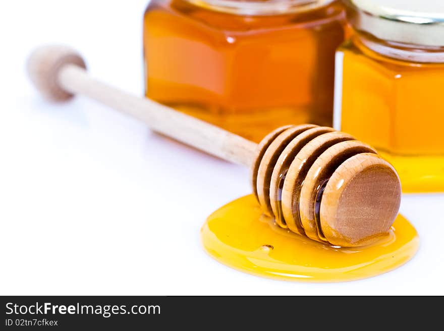 Detail of dipper with honey in front of honey pots isolated on white studio background. Detail of dipper with honey in front of honey pots isolated on white studio background.