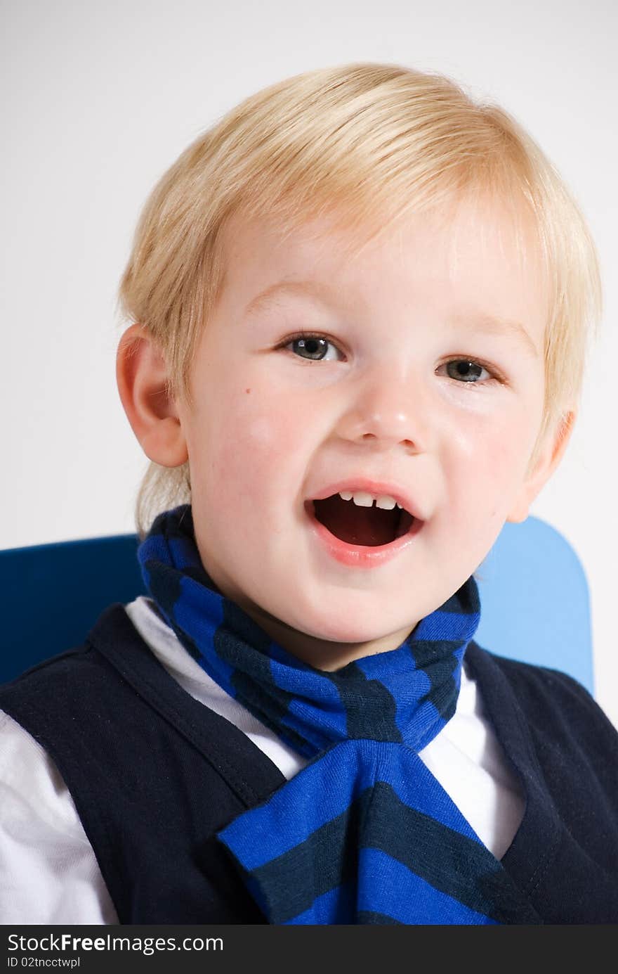 A vertical image of a lovely young blonde boy laughing and smiling