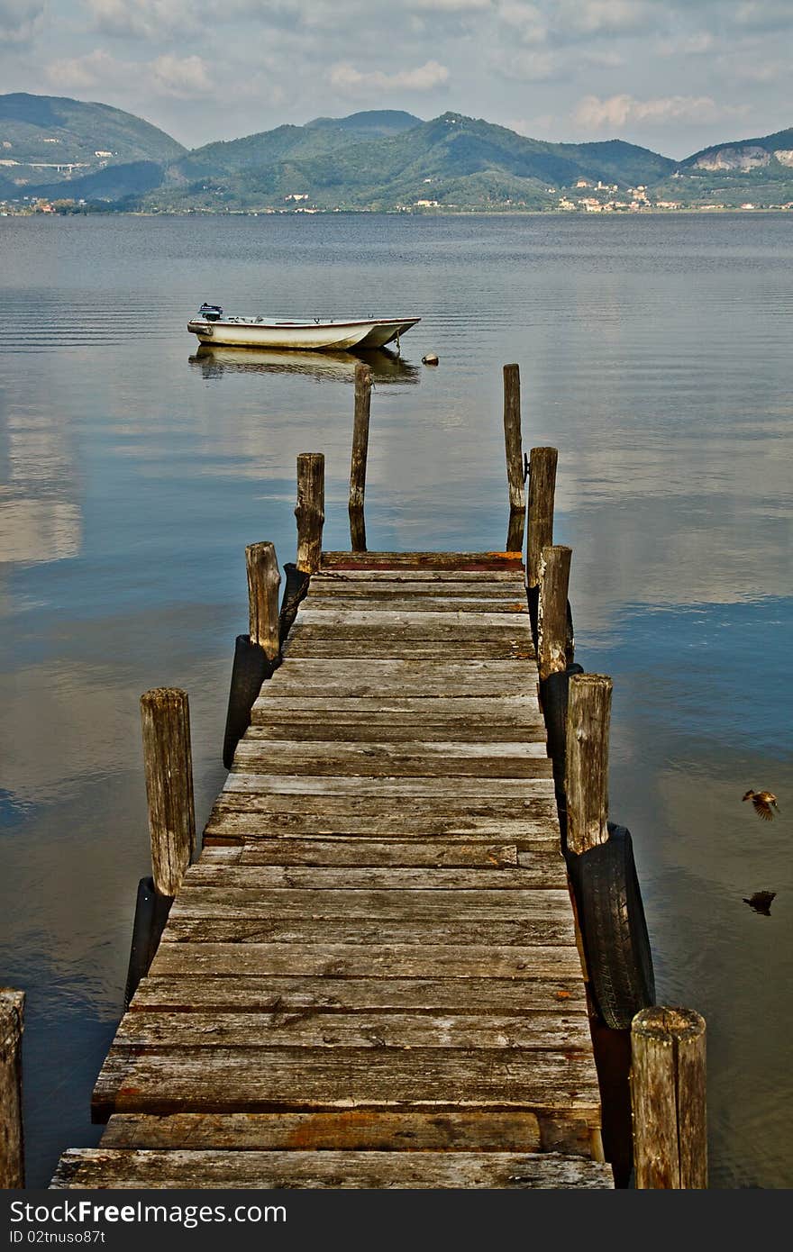 Wooden pier and boat on Lake Massaciuccoli. Lucca Tuscany, Italy