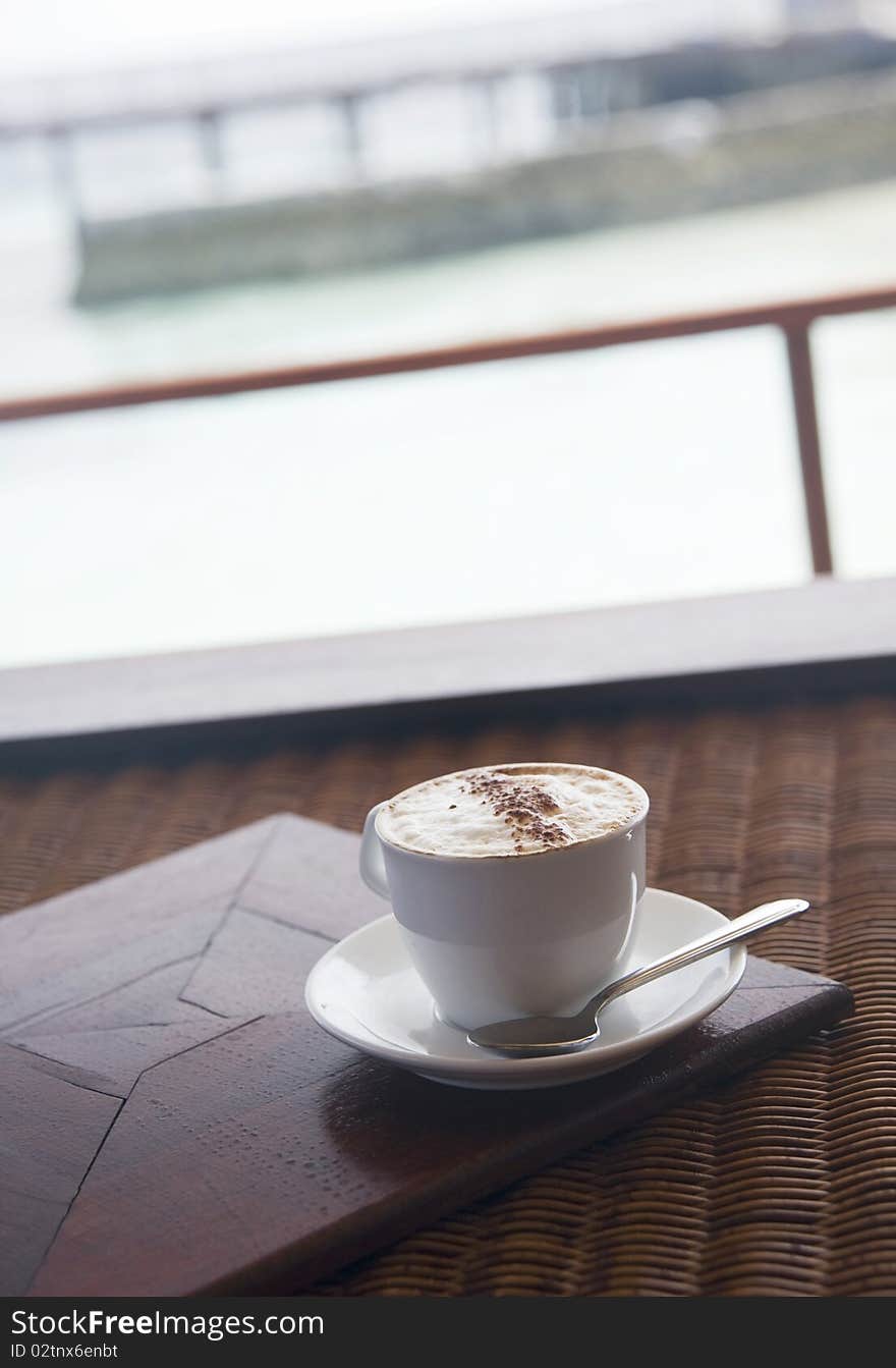 A cup of coffee with ocean at the background