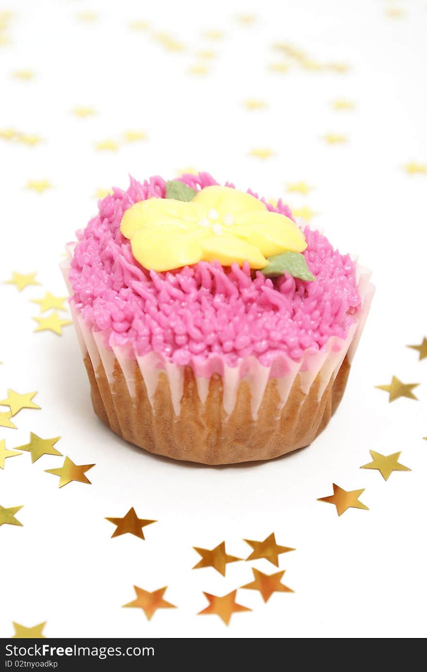 A pink frosted cupcake surrounded by star confetti.