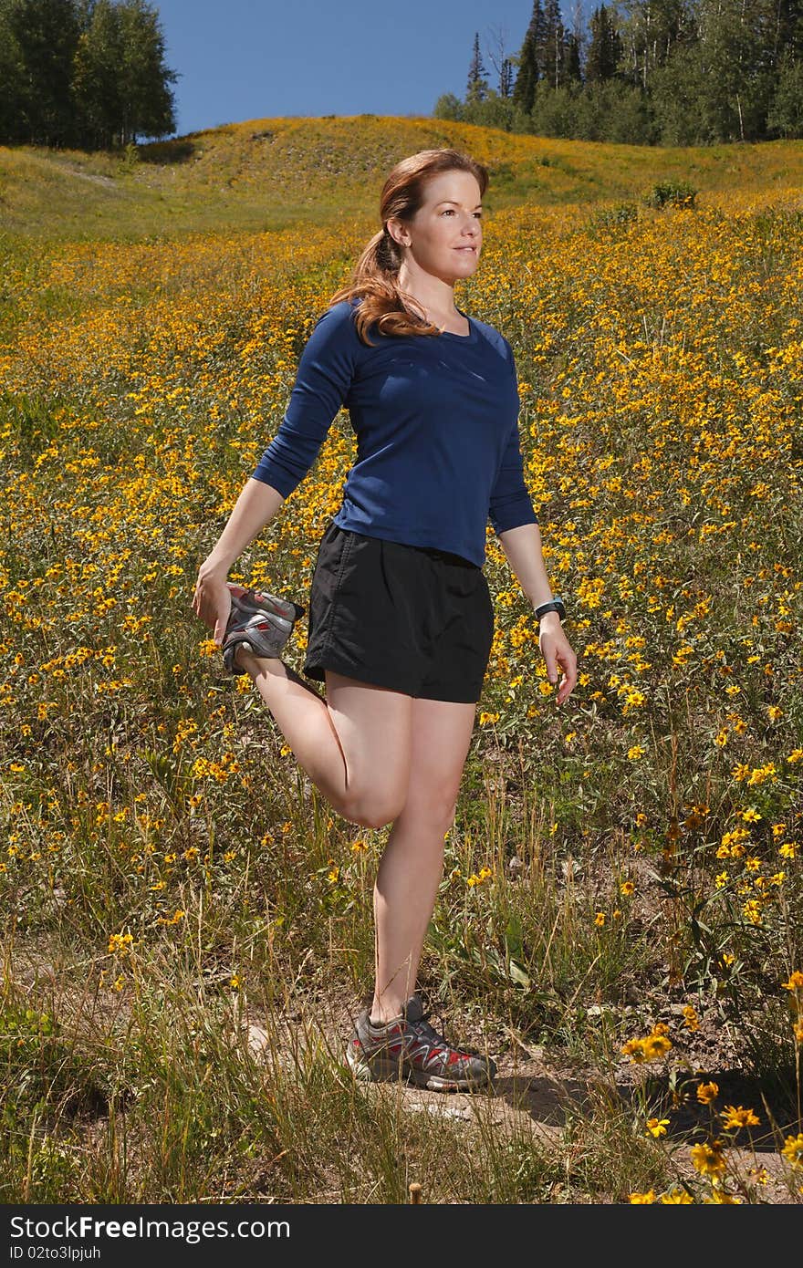 Young woman stretching her quadriceps on a trail. Young woman stretching her quadriceps on a trail.