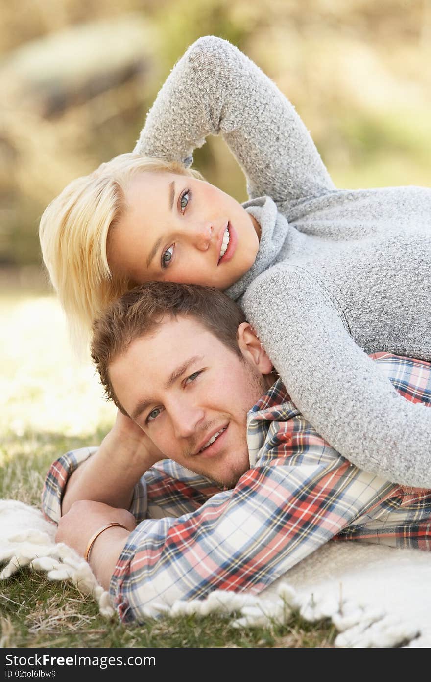 Portrait Of Romantic Young Couple Lying On Grass in the sun