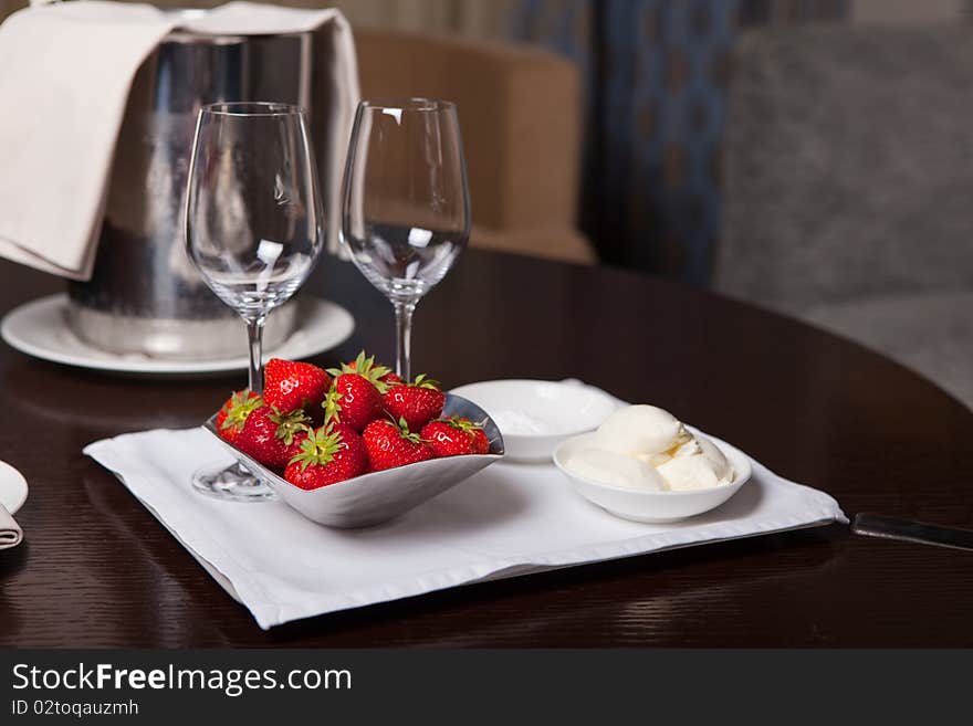 Two glasses for champagne and bunch of fresh strawberry at the table