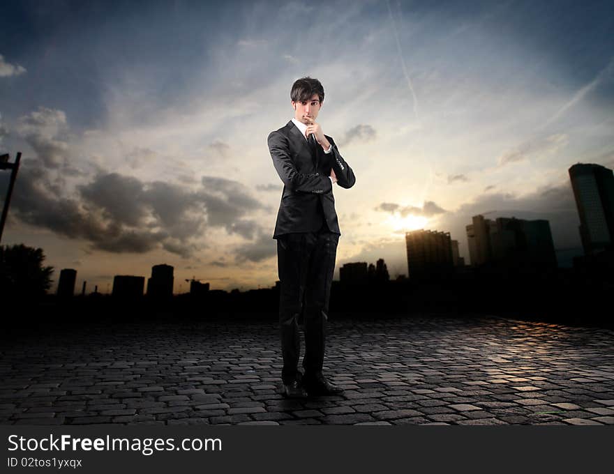 Businessman reflecting with sunset over a city on the background. Businessman reflecting with sunset over a city on the background