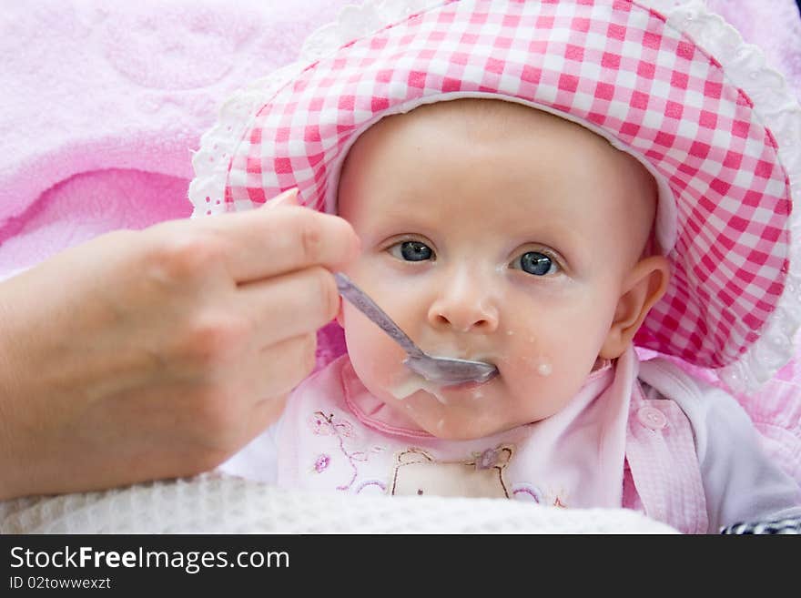 Little girl sits in a carriage and she is fed from a spoon. Little girl sits in a carriage and she is fed from a spoon