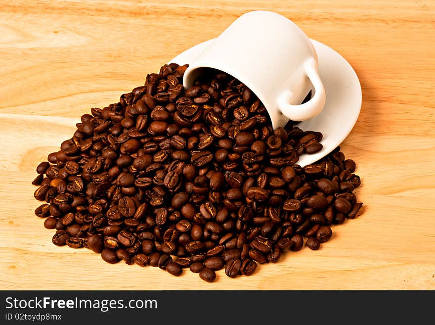 Coffe Beans spilling out of white cup and saucer. Coffe Beans spilling out of white cup and saucer