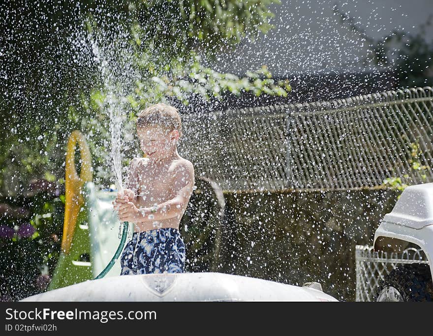 Young boy playing with a hose pipe in the Garden on a sunny day. Young boy playing with a hose pipe in the Garden on a sunny day