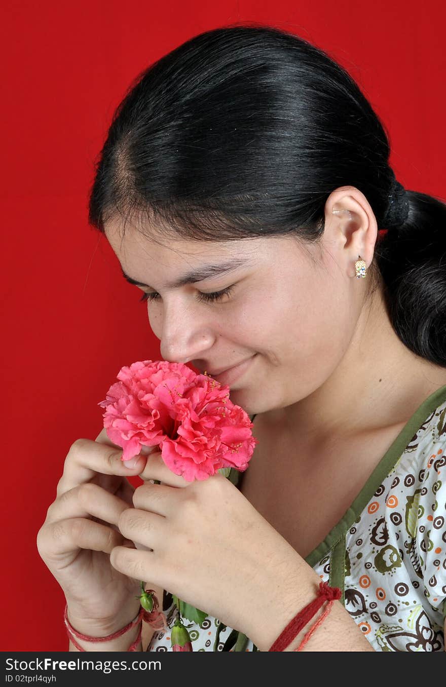 Beautiful girl smelling red flower