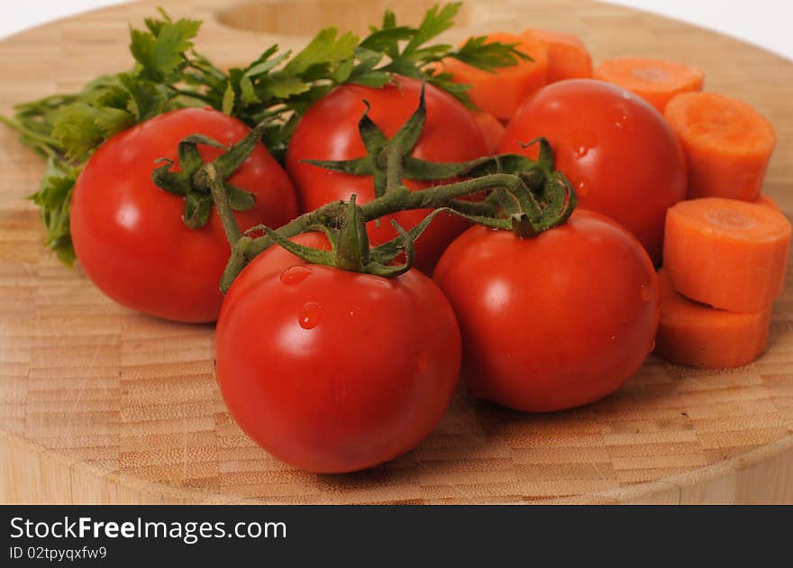 Fresh tomatoes, carrots and parsley on a wooden cutting board. Fresh tomatoes, carrots and parsley on a wooden cutting board