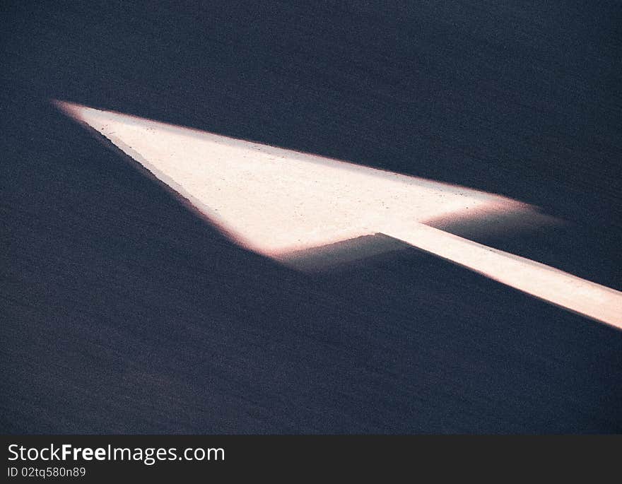 Blurred white arrow painted on tarmac road. Blurred white arrow painted on tarmac road