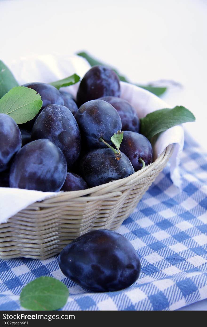 Many plums in a basket on a blue napkin