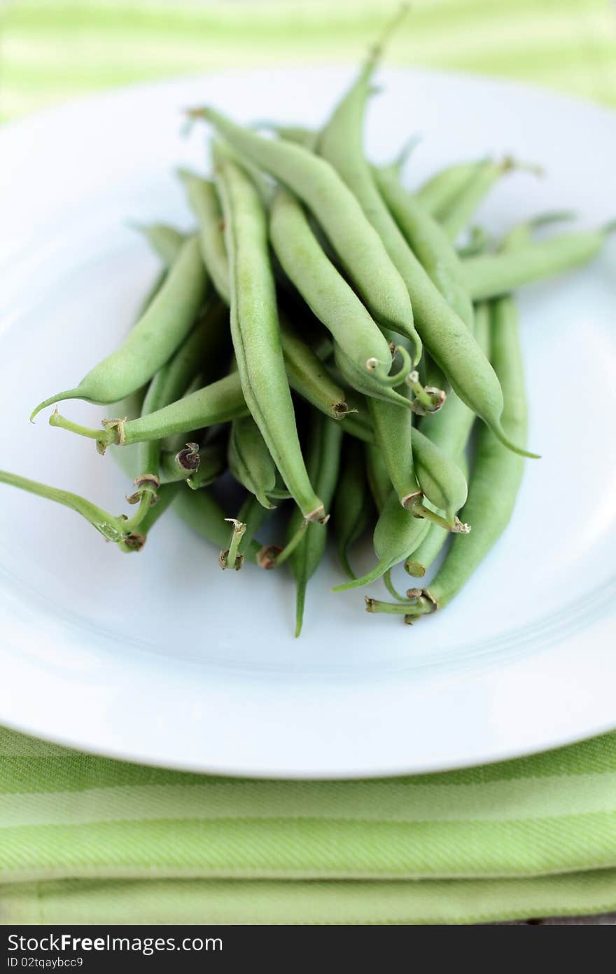 Green peas on a white plate with a green cloth