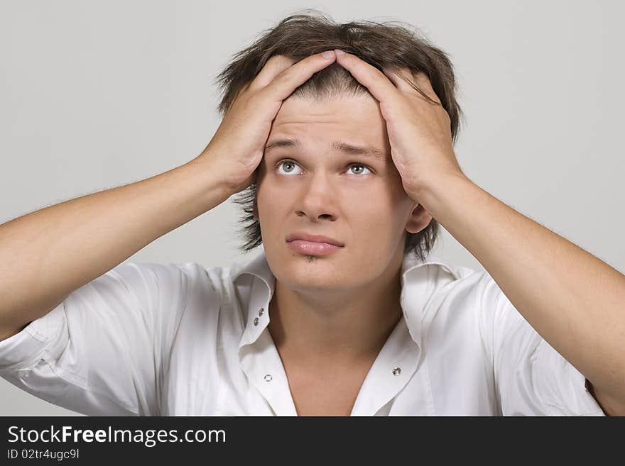 Closeup portrait of a upset young man with hand on his head