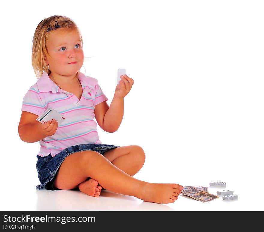 A 2-year-old girl paying with game pieces: dominoes, cards, money. Isolated on white. A 2-year-old girl paying with game pieces: dominoes, cards, money. Isolated on white.