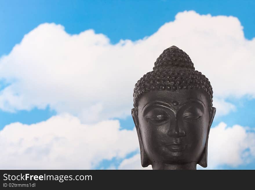 A peacefull Budha statue against a blue cloudy sky