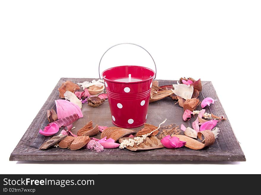 A candle in a bucket on a wooden plate with potpourri isolated over white. A candle in a bucket on a wooden plate with potpourri isolated over white