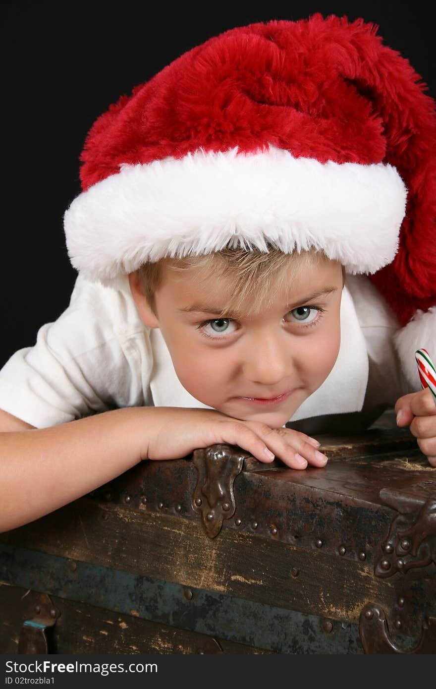 Cute young boy lying on an antique trunk wearing a christmas hat. Cute young boy lying on an antique trunk wearing a christmas hat