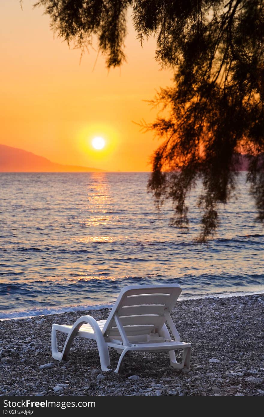 Chair on beach at sunset