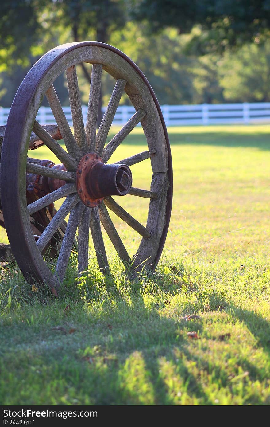 Rustic wagon wheel casting shadow on grass. Rustic wagon wheel casting shadow on grass