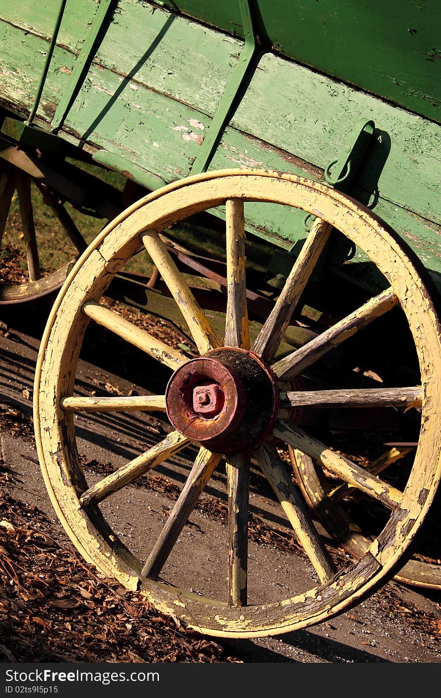 Rustic yellow wagon wheel on green cart