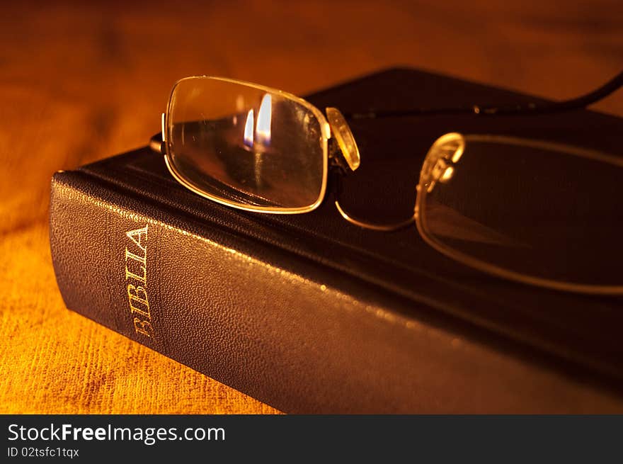 Bible and glasses with flame reflections on the lens. Bible and glasses with flame reflections on the lens