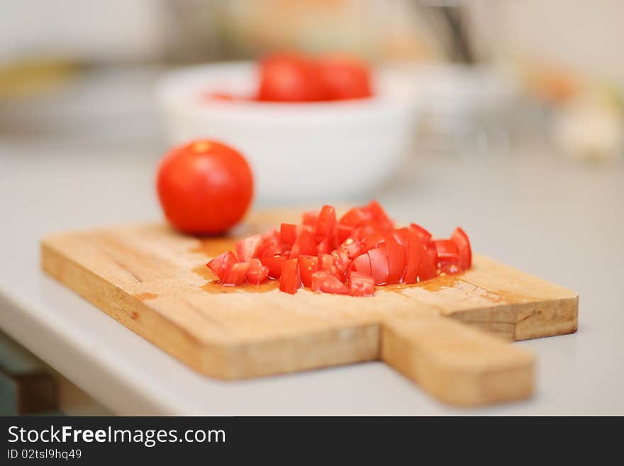 Sliced tomatoes on a wooden cutting board with a whole tomato in the background