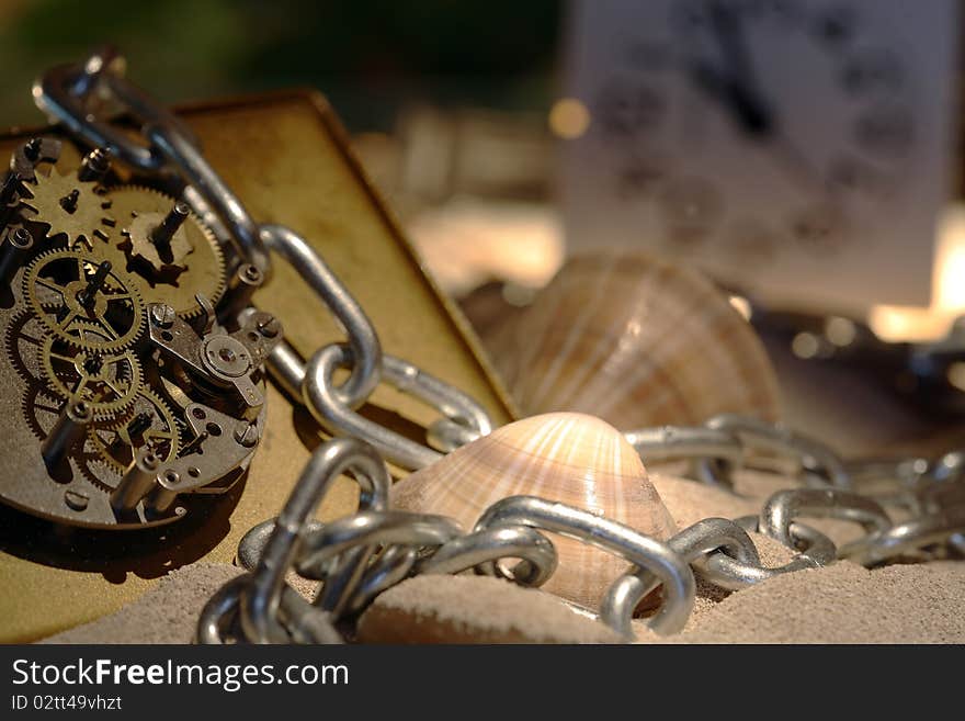 Abstract background with old clock mechanism standing on sand with stones and shells and chain. Abstract background with old clock mechanism standing on sand with stones and shells and chain