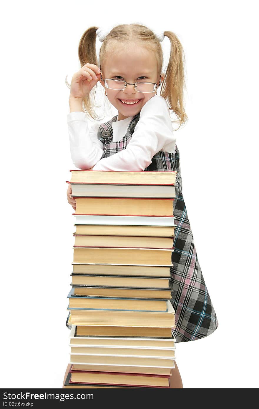 Cute funny little schoolgirl standing behind the books with glasses on laughing studio shot on white background. Cute funny little schoolgirl standing behind the books with glasses on laughing studio shot on white background