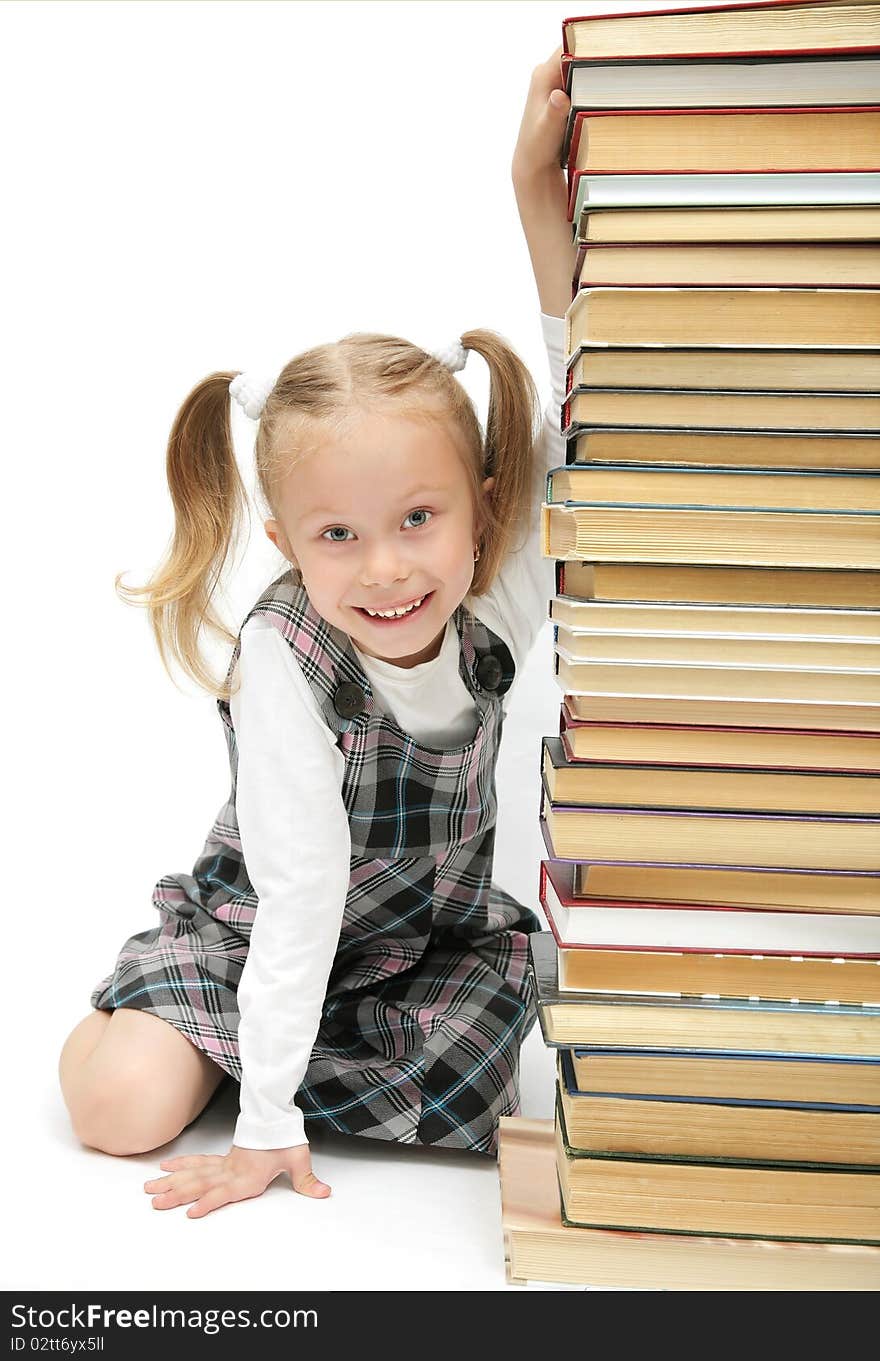 Cute funny little schoolgirl hiding behind the books and laughing  studio shot on white background. Cute funny little schoolgirl hiding behind the books and laughing  studio shot on white background